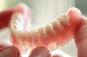 Hand holding a full denture