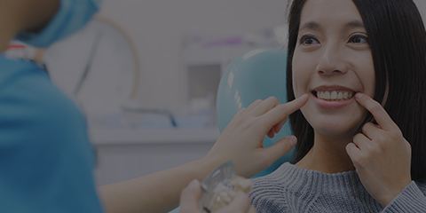 Woman in dental chair pointing to tooth